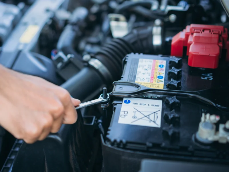 A mechanic secures a car battery mount