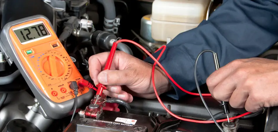 A mechanic uses a multimeter to test a car battery